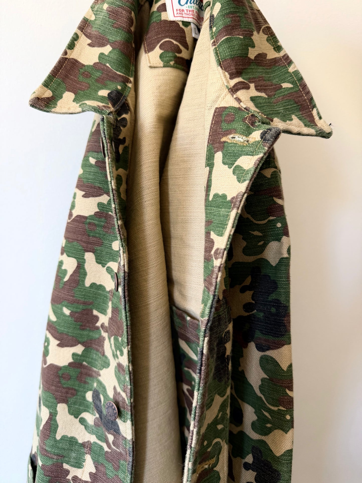 Chilao x Rivi Goods chore coat in camo hanging close up