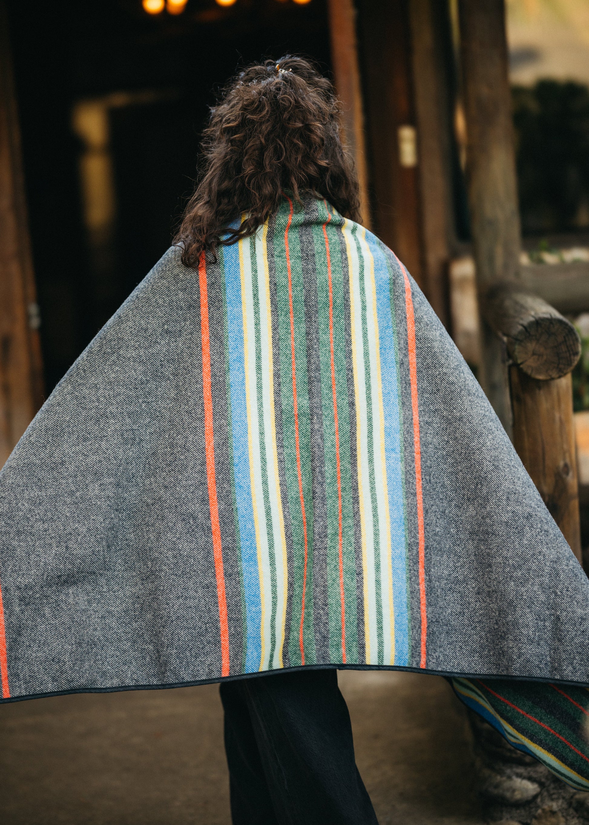 Person wearing a striped poncho with a blurred cabin background