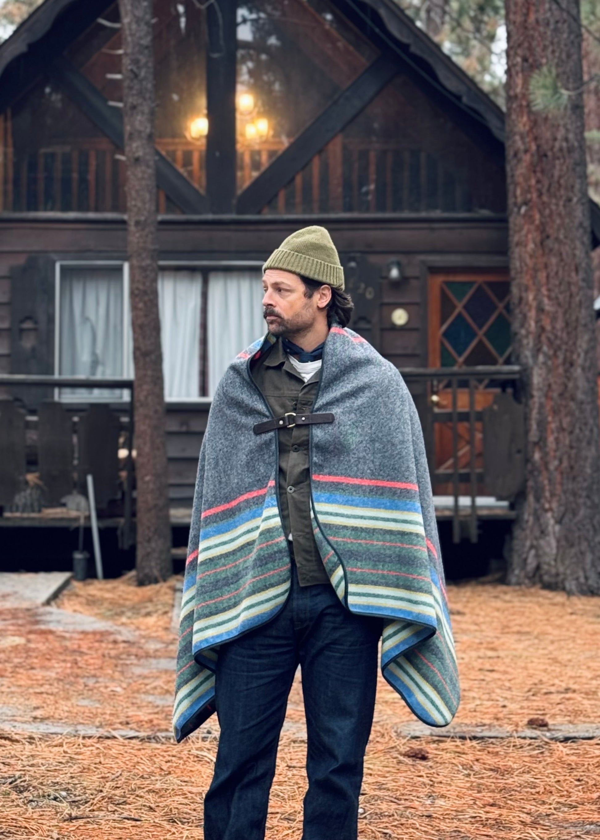 Model wearing Chilao's Pine Mountain Poncho in from of a cabin in Big Bear, CA