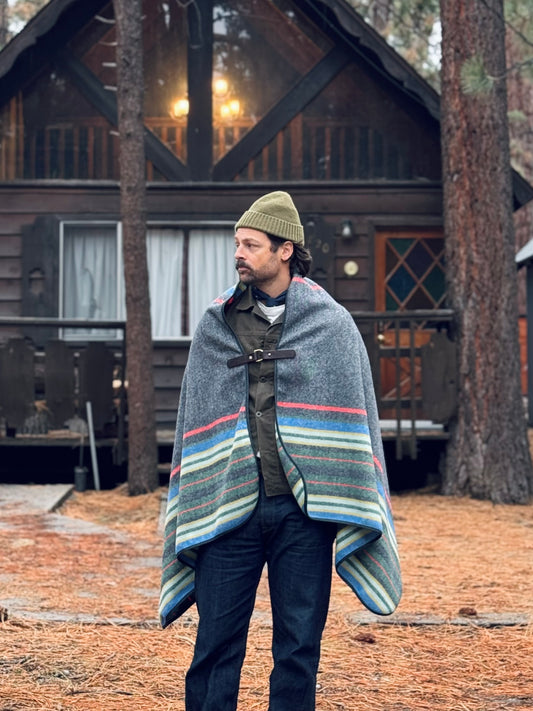 Model wearing Chilao's Pine Mountain Poncho in from of a cabin in Big Bear, CA