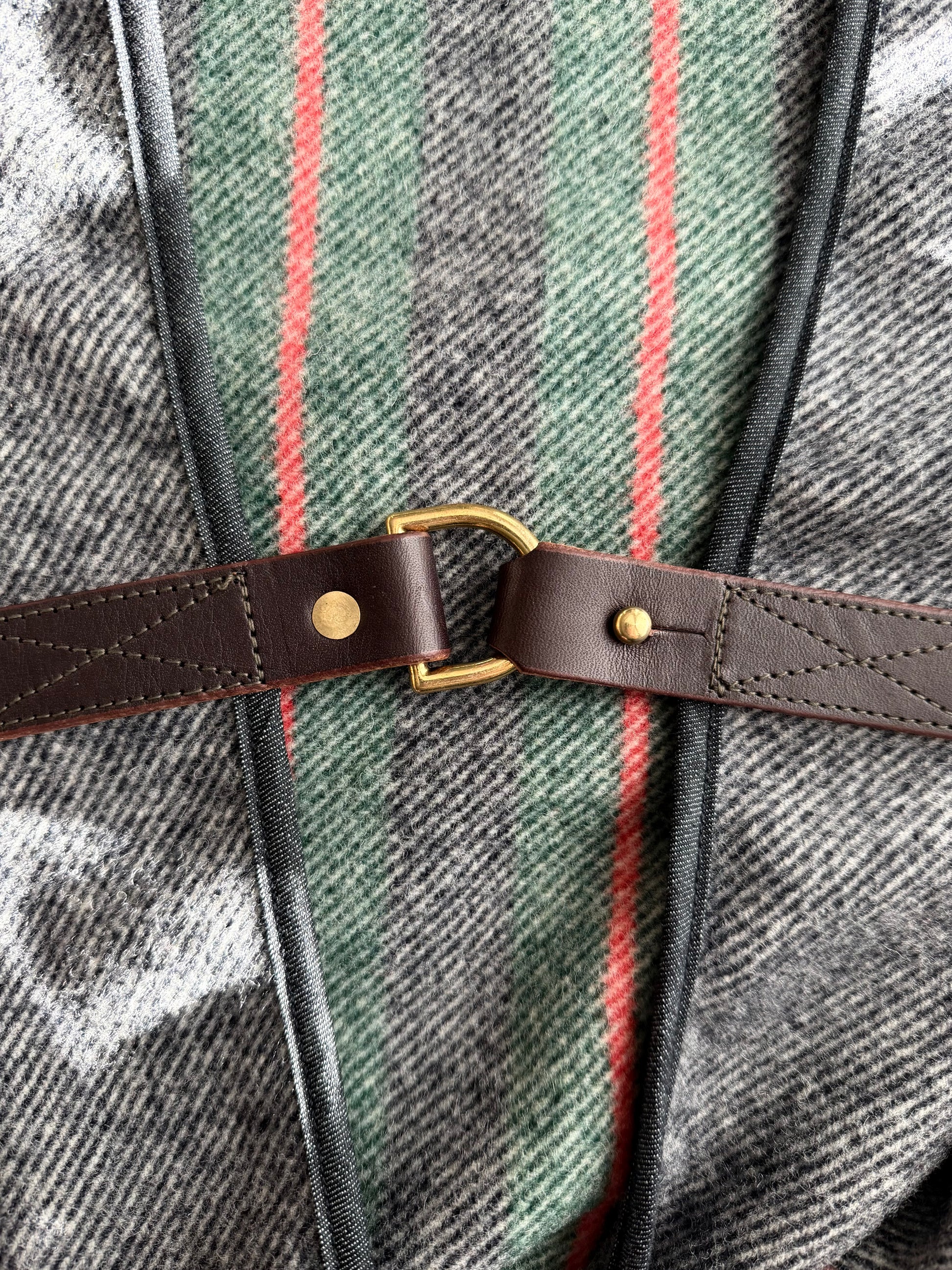 Close-up of grey striped wool fabric and brass hardware on Pine Mountain Poncho